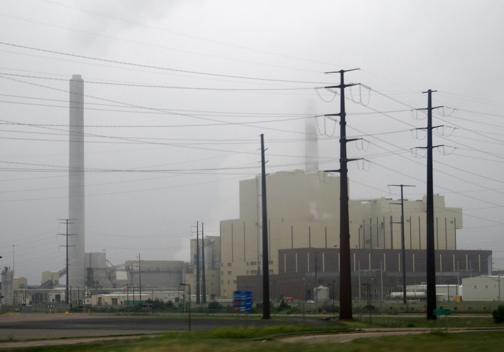 A power plant on a foggy day with transmission lines in the foreground.